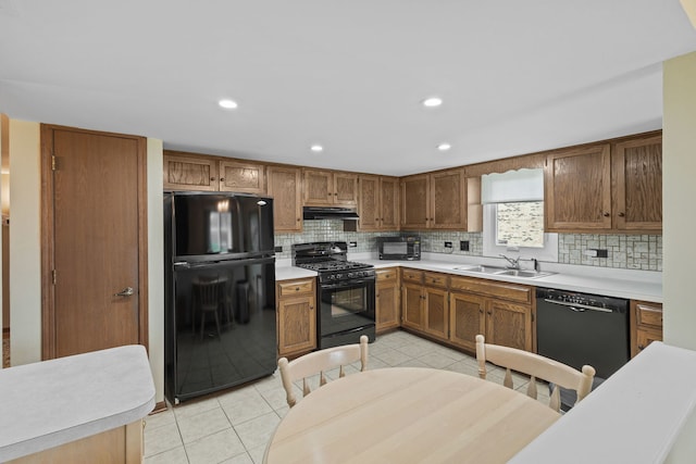 kitchen featuring a sink, light tile patterned flooring, black appliances, under cabinet range hood, and backsplash
