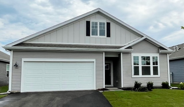 view of front of house featuring board and batten siding, asphalt driveway, a front lawn, and a garage