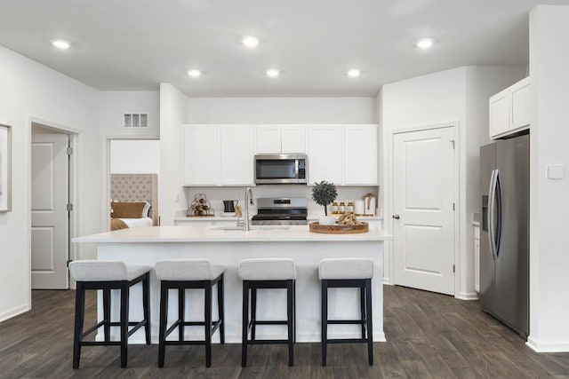 kitchen featuring stainless steel appliances, a sink, white cabinetry, a kitchen breakfast bar, and recessed lighting