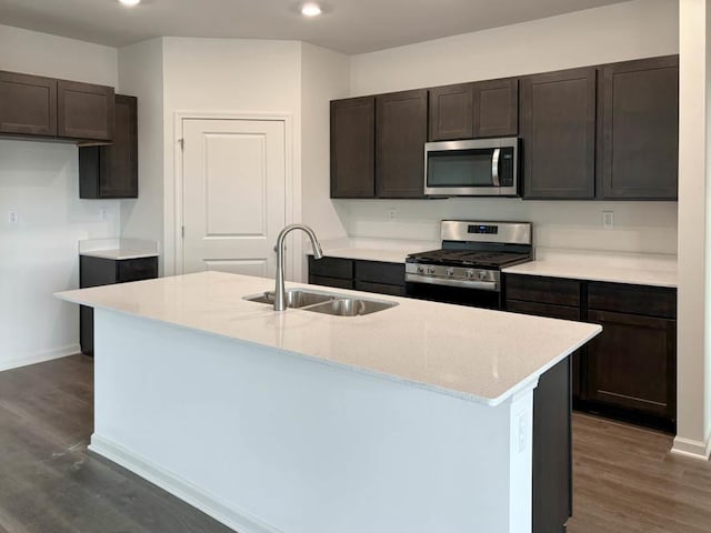 kitchen with appliances with stainless steel finishes, a sink, dark wood finished floors, recessed lighting, and dark brown cabinetry