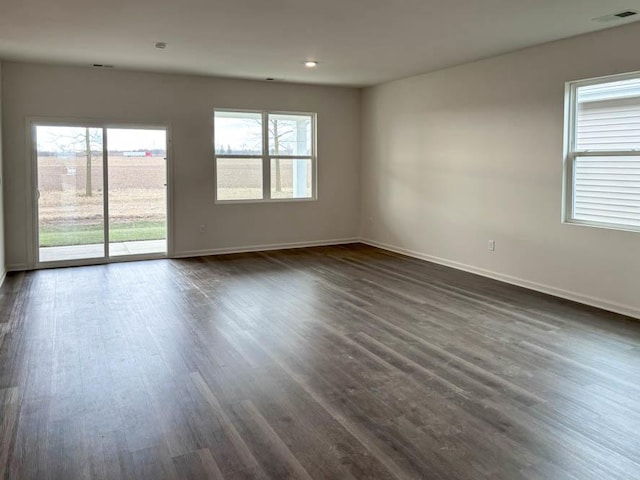 spare room with baseboards and dark wood finished floors
