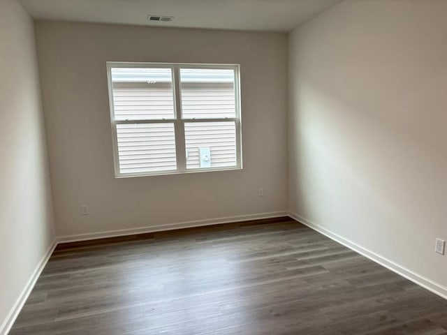 spare room featuring dark wood-style flooring and baseboards