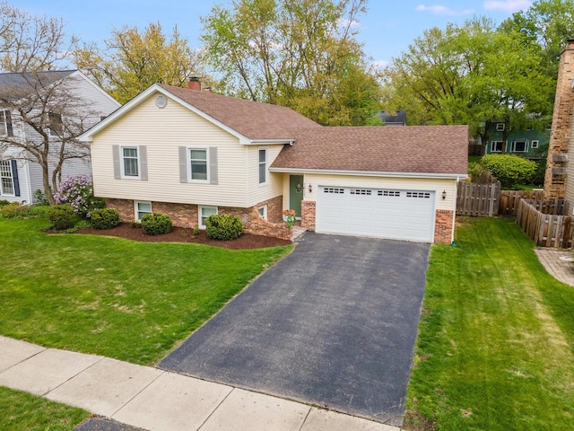split level home featuring a front yard, aphalt driveway, an attached garage, and fence
