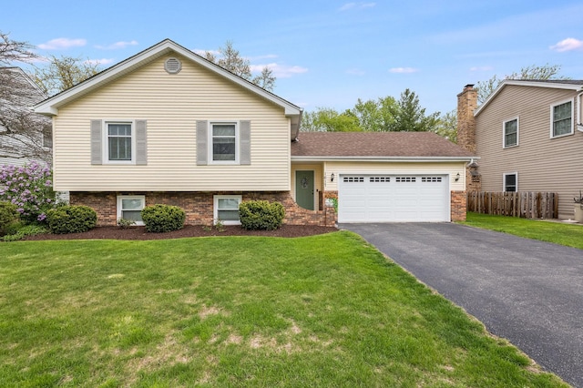 split level home featuring a front yard, driveway, fence, and a garage