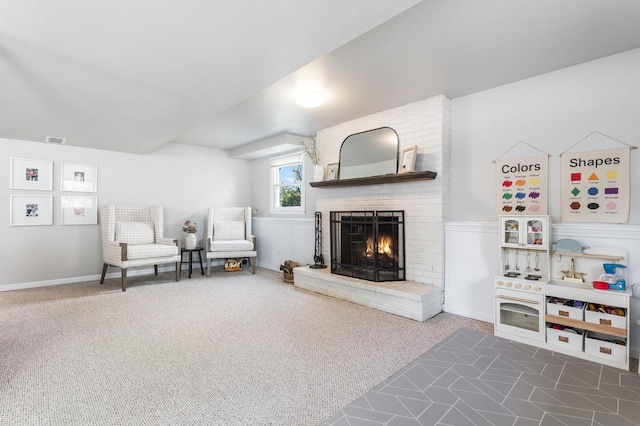 living area with a brick fireplace, carpet, and visible vents