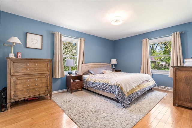 bedroom featuring baseboards, multiple windows, and light wood-type flooring