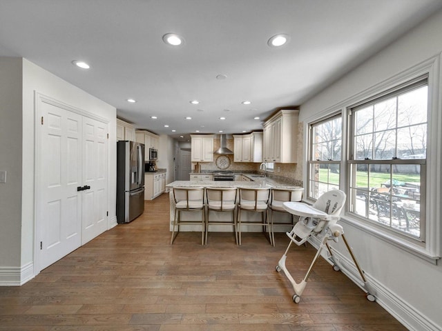 8 Wyndham Ct, Oak Brook, IL 60523 - kitchen with stainless steel appliances, wall chimney range hood, a peninsula, a sink, and wood finished floors