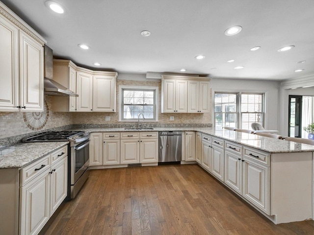 8 Wyndham Ct, Oak Brook, IL 60523 - kitchen featuring appliances with stainless steel finishes, wall chimney range hood, a peninsula, a sink, and hardwood / wood-style floors