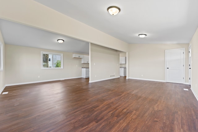 237 N Simmons St, Stockton, IL 61085 - unfurnished living room featuring visible vents, dark wood-style flooring, and baseboards