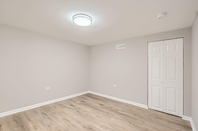 empty room with baseboards, light wood-style flooring, and visible vents
