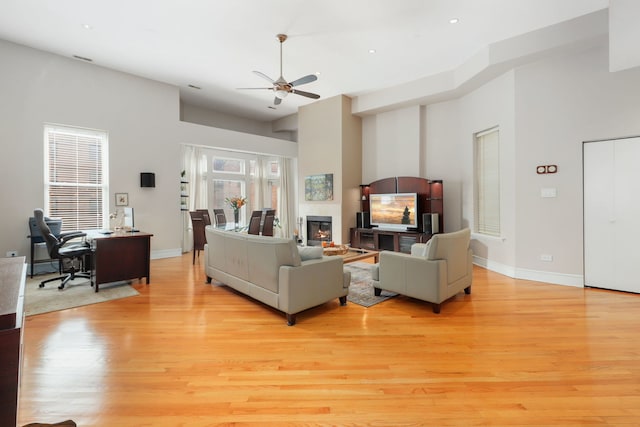 living room with recessed lighting, baseboards, a glass covered fireplace, ceiling fan, and light wood-type flooring