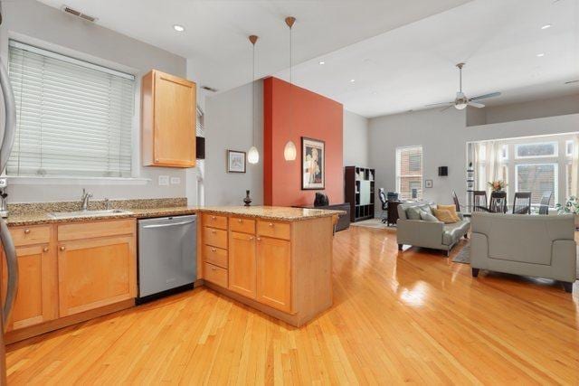 kitchen with a peninsula, light wood finished floors, a ceiling fan, open floor plan, and dishwasher