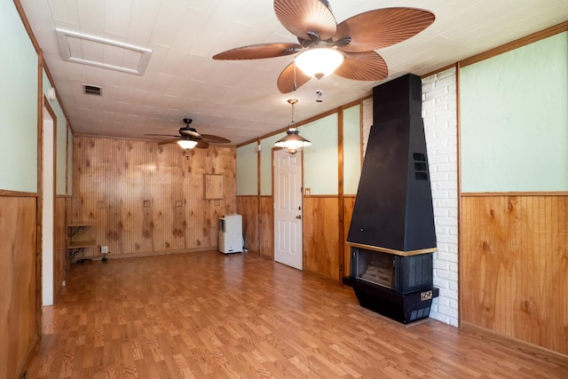 720 Suffolk Pl, Streamwood, IL 60107 - unfurnished living room with wood walls, ceiling fan, wood finished floors, a wood stove, and a wainscoted wall