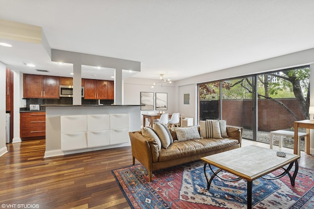 living room featuring dark wood-type flooring, healthy amount of natural light, recessed lighting, and a chandelier