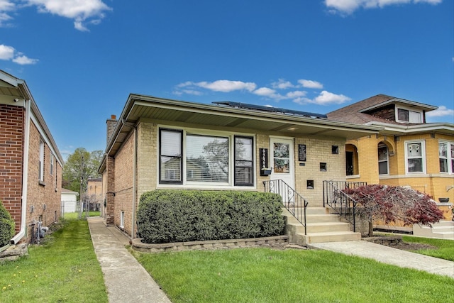 bungalow-style house featuring a front lawn, roof mounted solar panels, brick siding, and a porch
