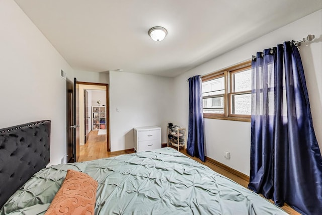 bedroom with baseboards, visible vents, and wood finished floors