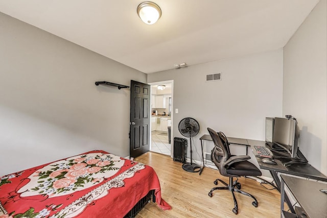 bedroom featuring light wood-style flooring, ensuite bath, and visible vents