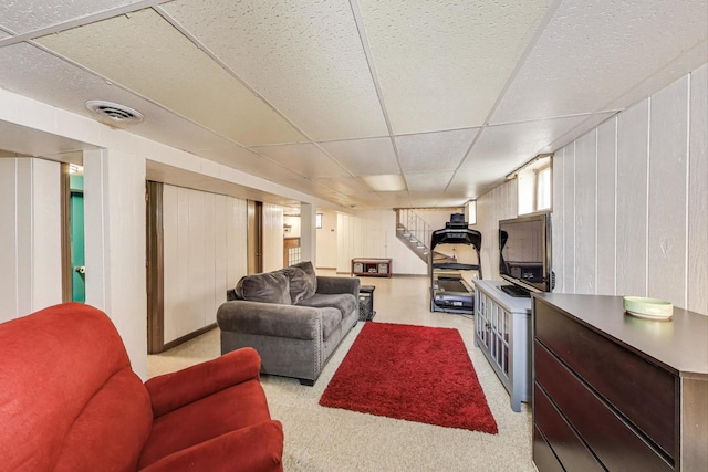 living area with stairs, a drop ceiling, visible vents, and light colored carpet