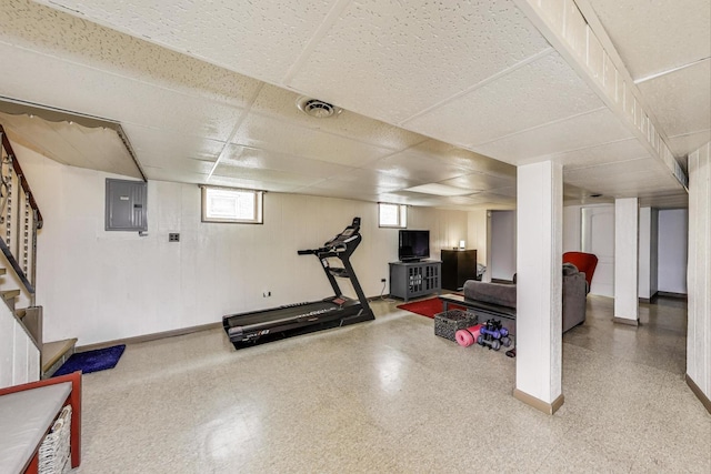 exercise room with electric panel, baseboards, a paneled ceiling, and visible vents