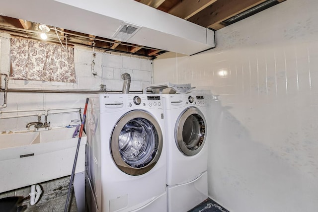laundry area featuring laundry area, washer and clothes dryer, visible vents, and a sink