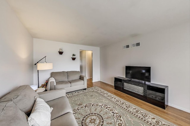living room with baseboards, visible vents, and wood finished floors