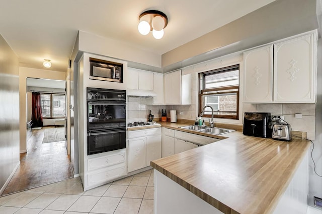 kitchen featuring a peninsula, white cabinetry, plenty of natural light, and a sink