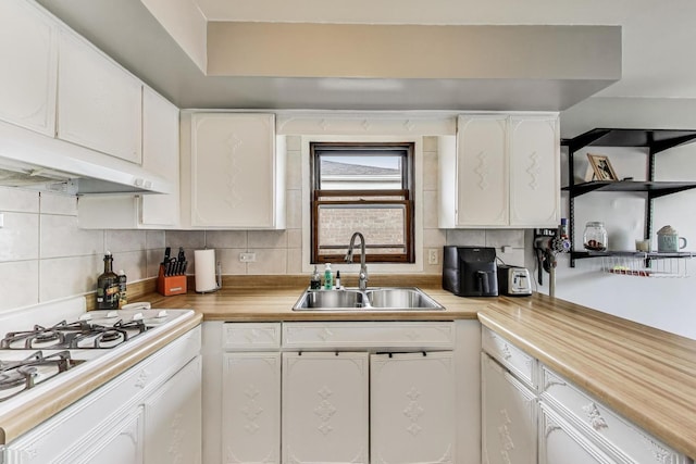 kitchen featuring a sink, white gas cooktop, white cabinetry, and backsplash