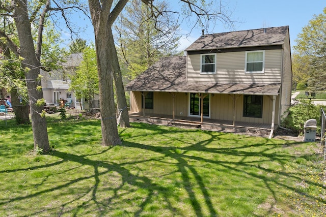 back of house featuring a yard, board and batten siding, a porch, and roof with shingles