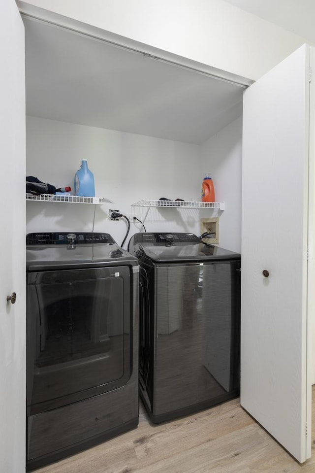 laundry room featuring washing machine and dryer and light wood-style floors