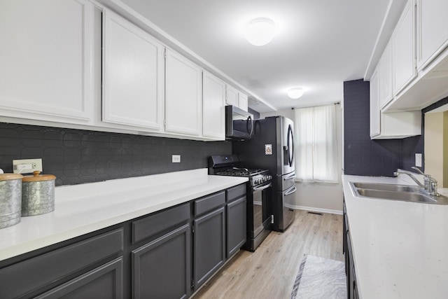 kitchen with gas range, stainless steel microwave, a sink, tasteful backsplash, and light wood-style flooring