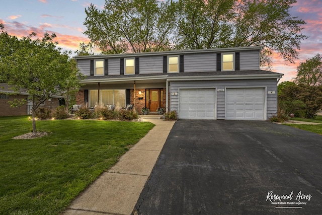 traditional-style house featuring asphalt driveway, a garage, and a front yard