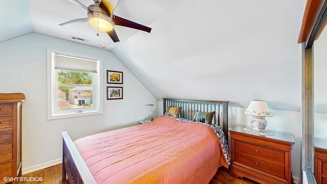 bedroom with wood finished floors, vaulted ceiling, baseboards, and ceiling fan