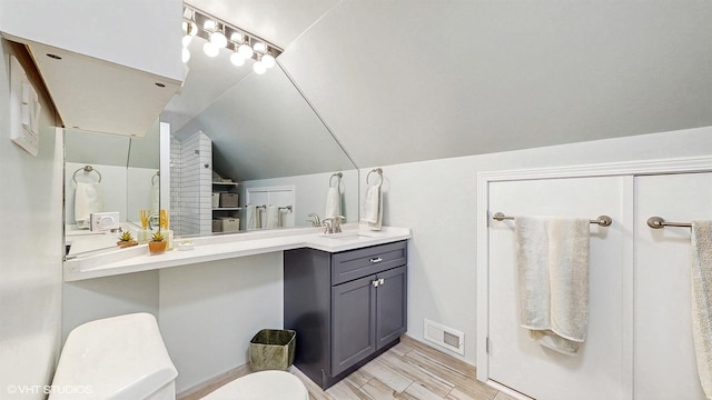 bathroom featuring toilet, vaulted ceiling, wood finished floors, and vanity