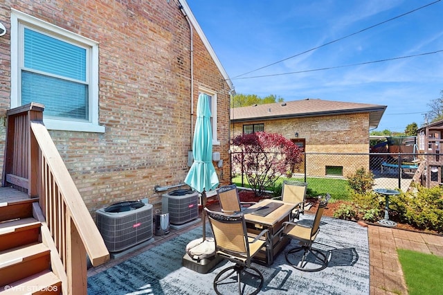 view of patio with central AC unit, fence, and outdoor dining area