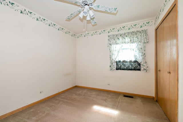 unfurnished room featuring a ceiling fan, light carpet, and baseboards