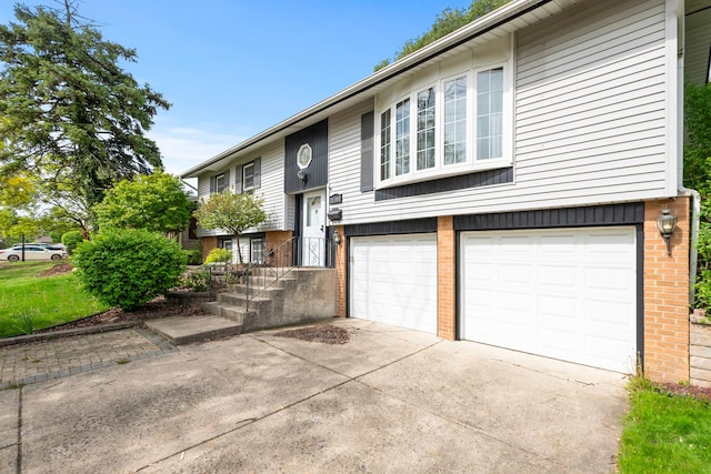 raised ranch featuring brick siding, driveway, and an attached garage
