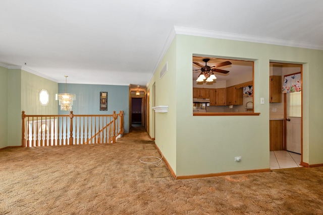 unfurnished room with carpet, a chandelier, ceiling fan, ornamental molding, and baseboards