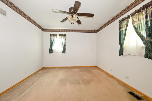 unfurnished room featuring light carpet, baseboards, crown molding, and ceiling fan