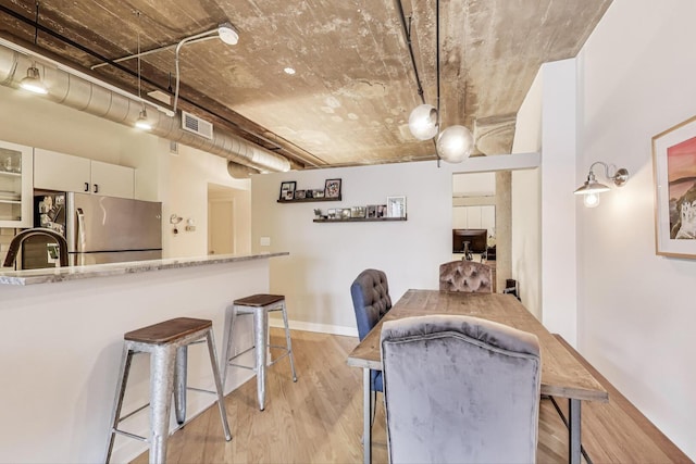 411 W Ontario St Unit 311, Chicago, IL 60654 - kitchen with freestanding refrigerator, a kitchen bar, light wood-type flooring, and visible vents