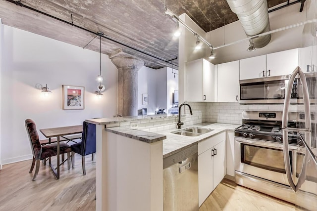 411 W Ontario St Unit 311, Chicago, IL 60654 - kitchen featuring light stone countertops, light wood finished floors, a sink, a peninsula, and stainless steel appliances