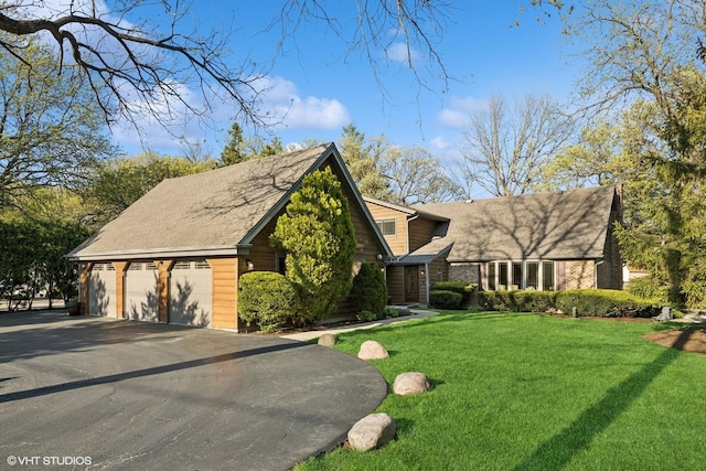 view of front of property with a front yard, a shingled roof, and a garage