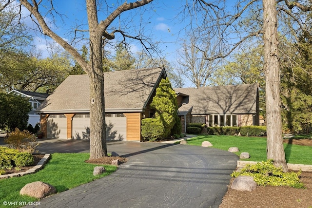 view of front facade with a front lawn, a shingled roof, and asphalt driveway