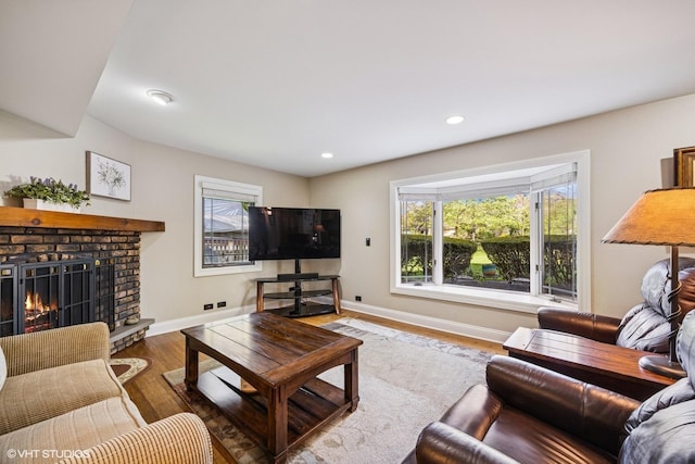 living room featuring wood finished floors, a brick fireplace, baseboards, and recessed lighting
