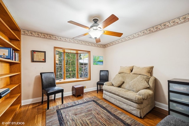 sitting room with ceiling fan, baseboards, and wood finished floors