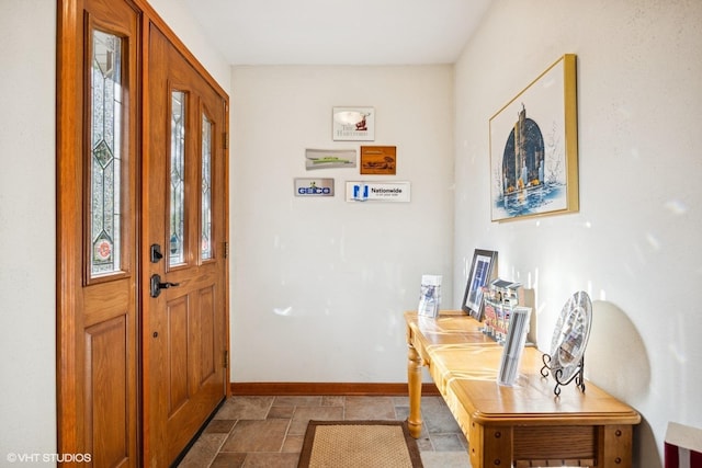 entrance foyer featuring baseboards and stone finish floors