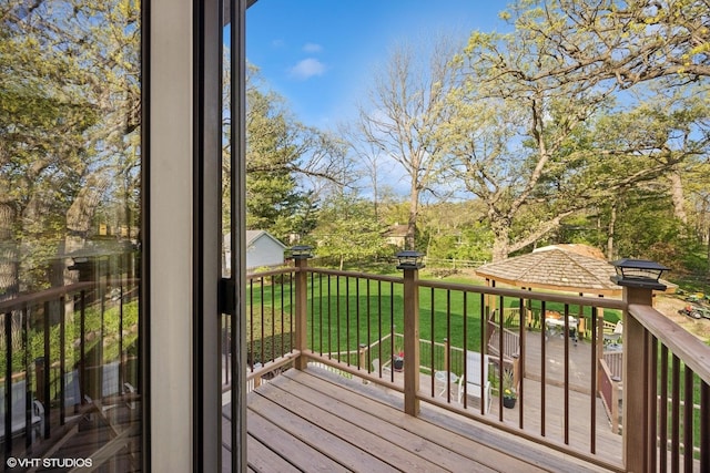 wooden deck featuring a lawn and view of wooded area