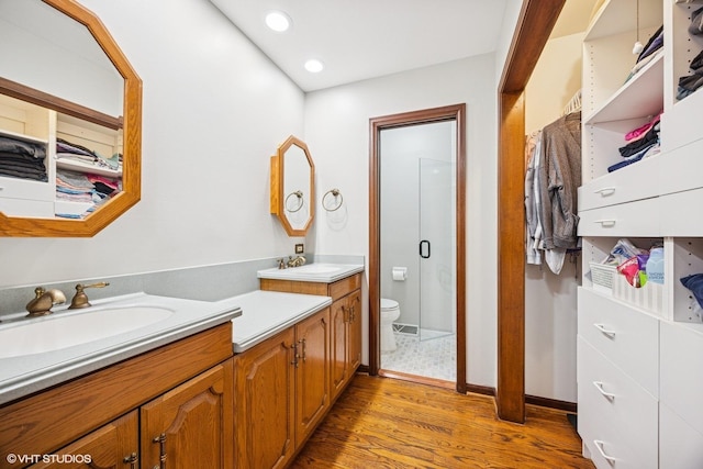 bathroom with wood finished floors, vanity, toilet, a shower stall, and recessed lighting