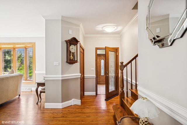 entryway with wood finished floors, crown molding, baseboards, and stairs