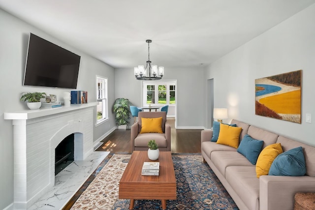 living area featuring a chandelier, baseboards, a fireplace, and marble finish flooring