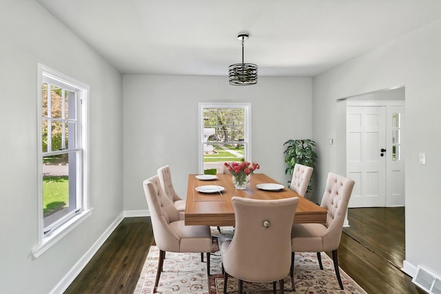 dining space featuring dark wood-type flooring and baseboards